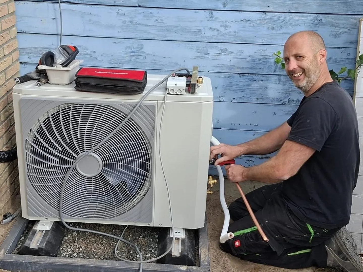 Monteur van Orivion sluit een buitenunit aan naast een woning