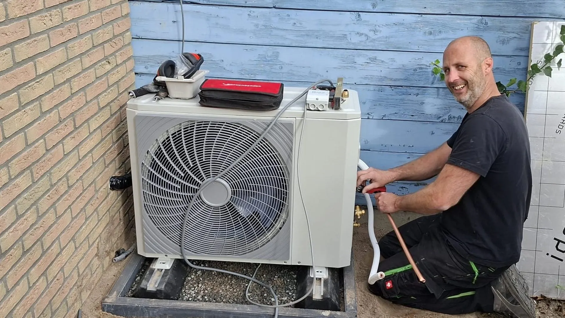 Monteur van Orivion sluit een buitenunit aan naast een woning